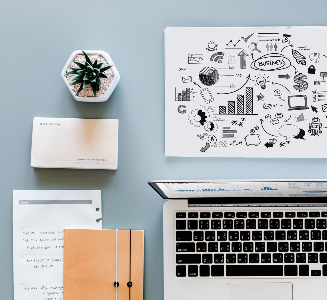 Desk filled with data icons, laptop, notebook 